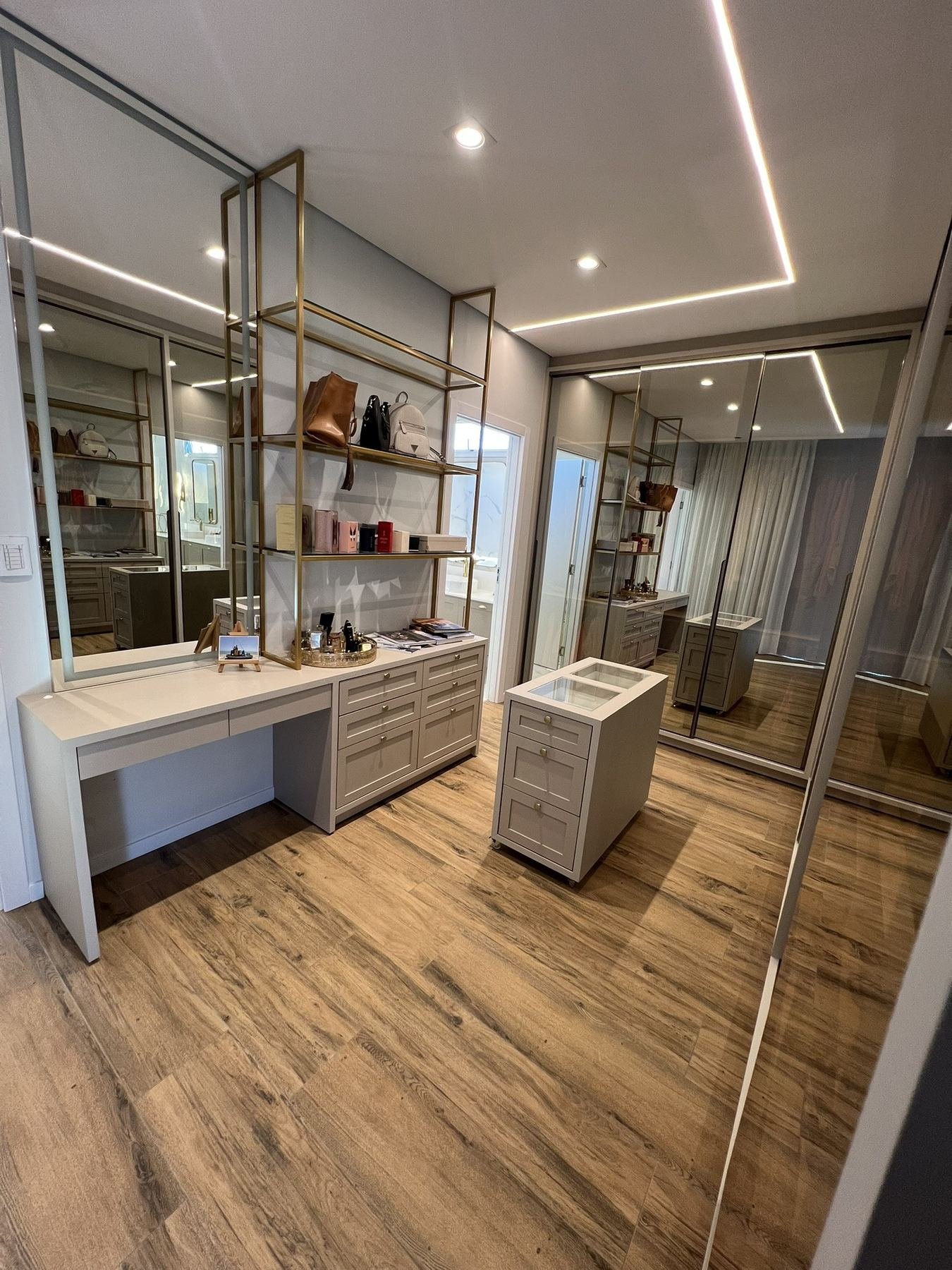 Closet planejado com bancada, prateleiras em metal dourado e vidro
