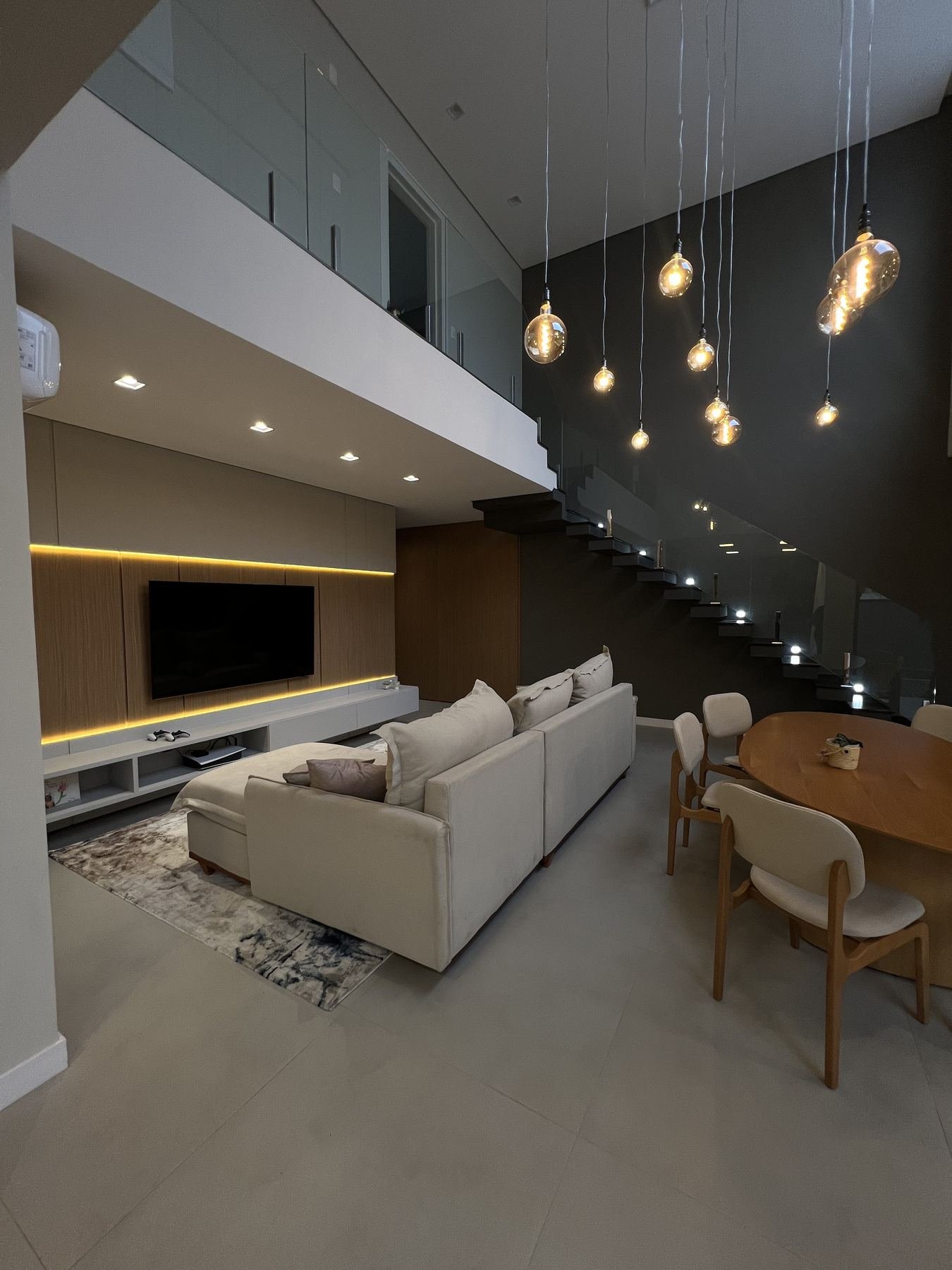 Sala de estar e jantar integradas, com painel de TV e mezanino