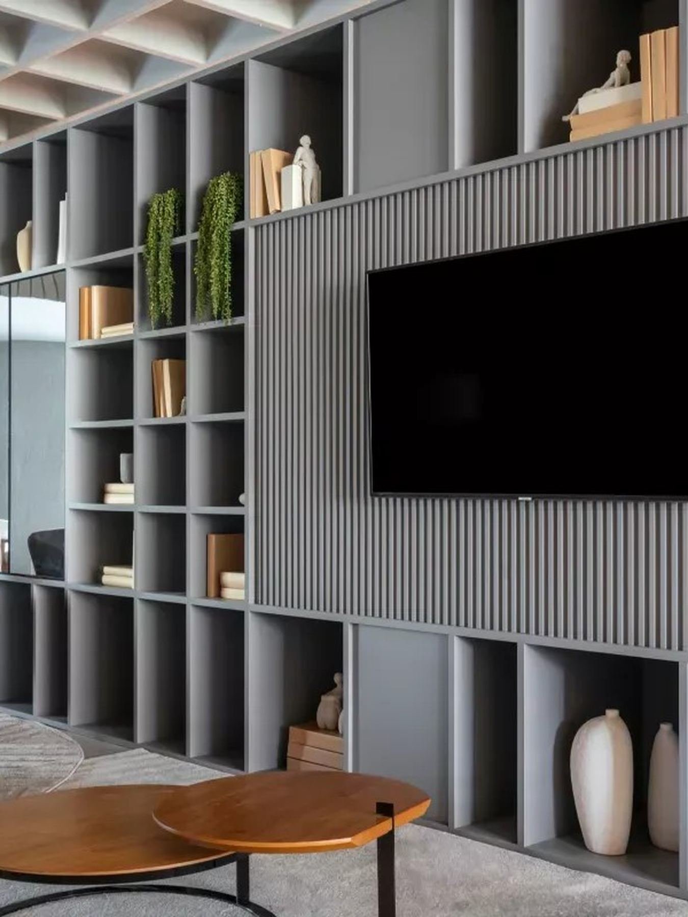 Sala de estar planejada com estante ripada, painel de TV e poltrona