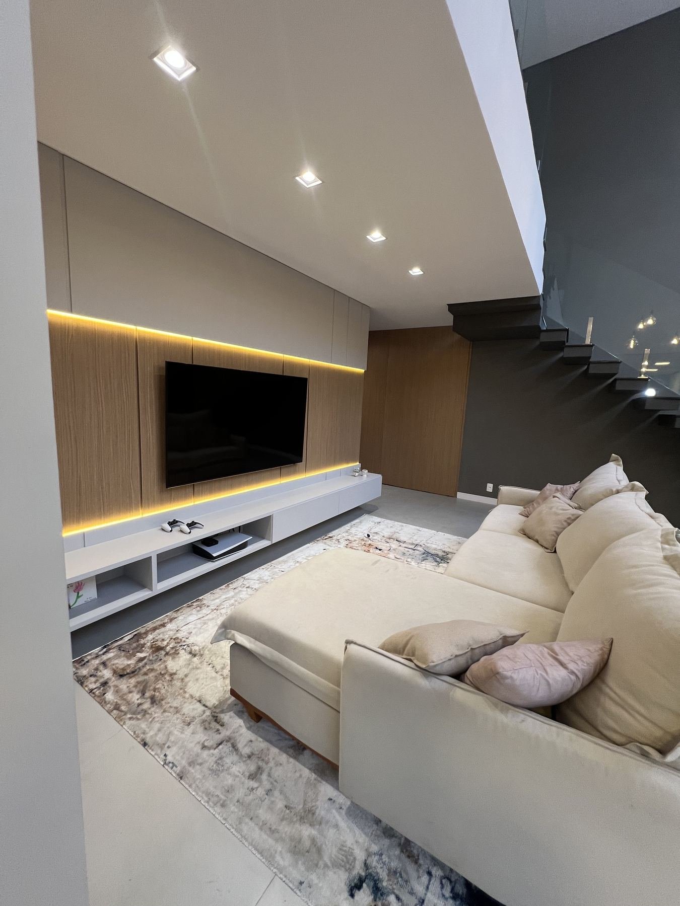 Sala de estar planejada com sofá, painel de TV e pé-direito duplo
